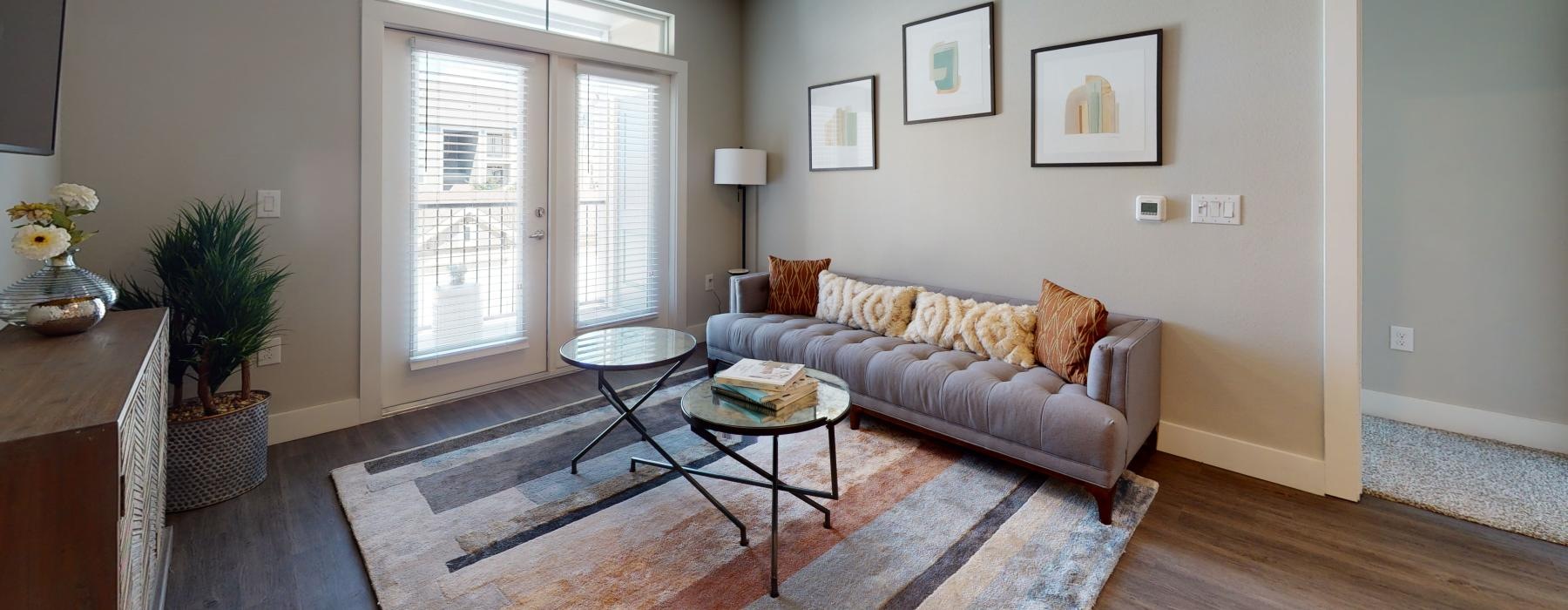 a living room with a couch and a table and glass door balcony
